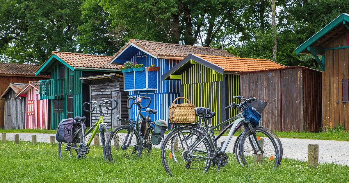 Cabanes ostréicoles colorées et vélos garés devant, dans un port du Bassin d’Arcachon