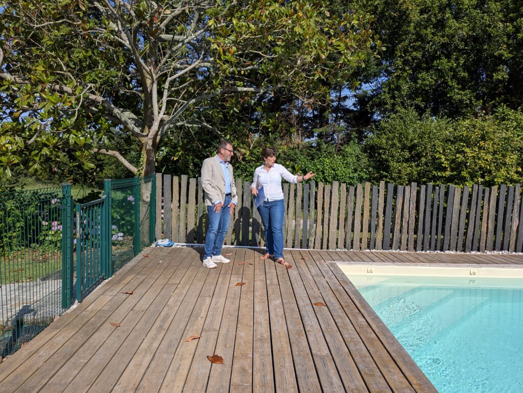 Audrey Guilloteaux en visite avec un acquéreur, autour de la terrasse et de la piscine d’une maison du Bassin d’Arcachon